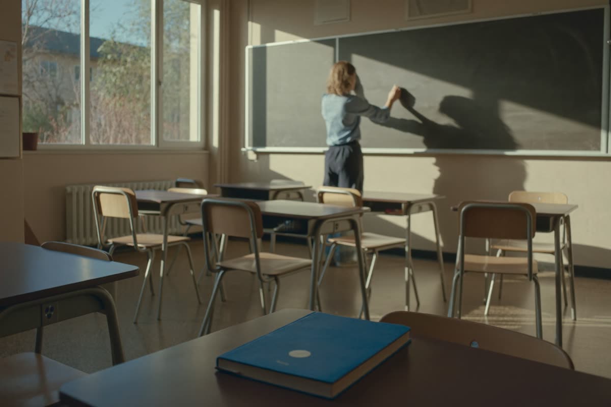 Lehrerin schreibt an eine Tafel in einem leeren Klassenraum